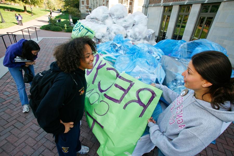 agnes Scott students talking while standing near large bags of recycled items.